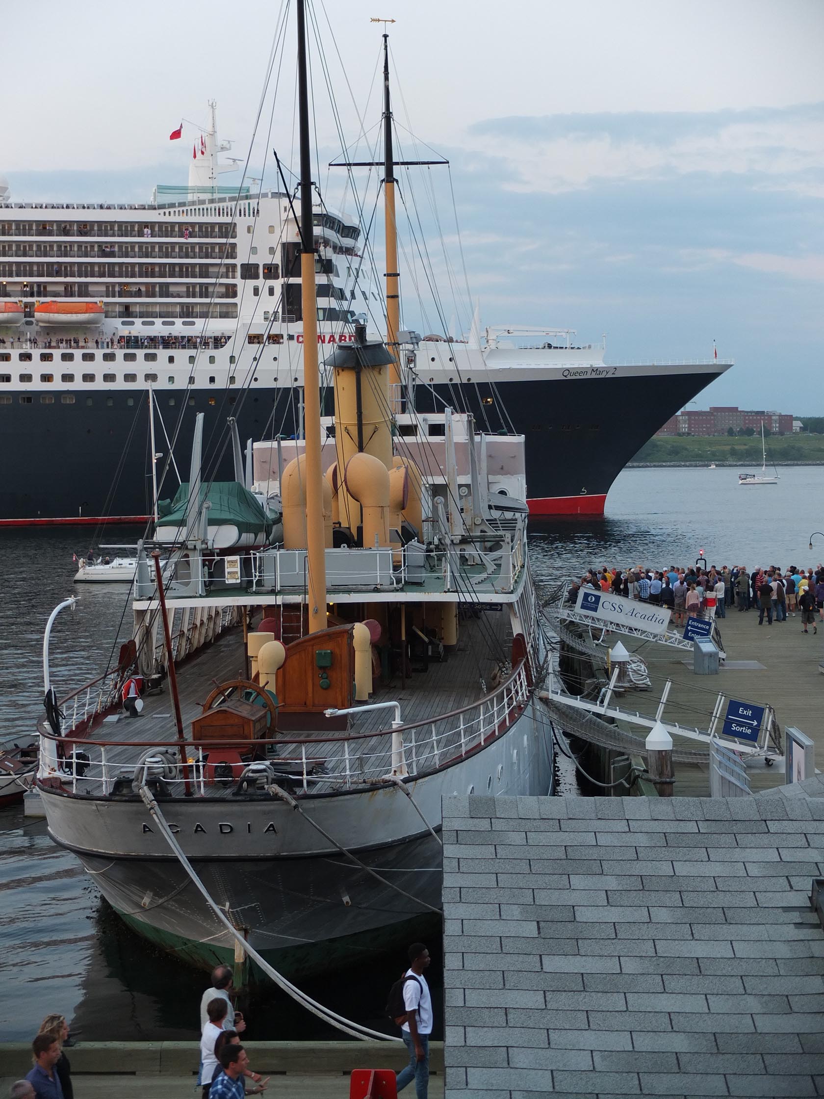 Crowds gather to watch the Cunnard Line's Queen Mary sail past the CSS Acadia